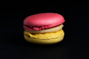 Sweet colored macaroon isolated on black background.