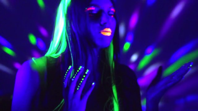 Fashion model woman in neon light. Beauty girl with fluorescent makeup. Party at night club. Slow motion 4K UHD video footage. 3840X2160
