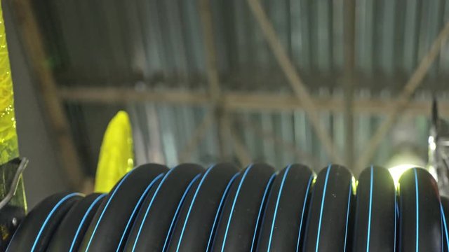 Roll threading coil pipe. Manufacture of plastic water pipes to the factory. Process of making plastic tubes on the machine tool with the use of water and air pressure.