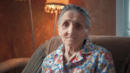 Portrait of an elderly woman 80-90 years old at home. Old odd lady with wrinkled skin face looking at camera. Detailed aged face skin. Great grandmother face expression. Senior granny female.