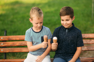 Children are sitting on the bench and eating icecream