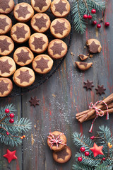 Christmas cookies with chocolate star pattern on cooling rack with spices and decorated fir twigs
