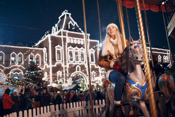 A young woman rides a merry-go-round with horses at the New Year's Fair