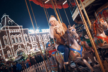 A young woman rides a merry-go-round with horses at the New Year's Fair
