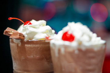 two glasses with a milky neck with a cherry against the window