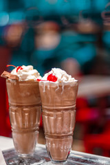 two glasses with a milky neck with a cherry against the window