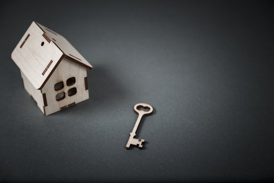 Real estate concept. Small toy wooden house with keys on grey background