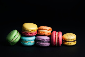 Pile of sweet and colourful french macaroons on black background.