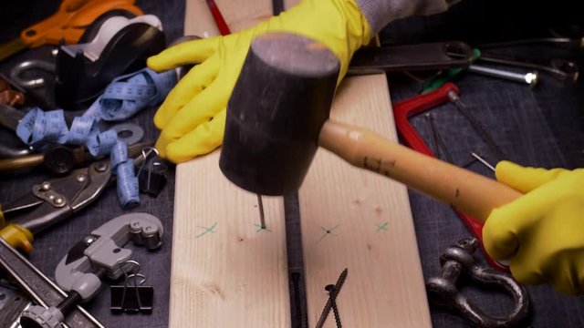 THE WRONG TOOL FOR THE JOB.  #2 IN A SERIES.  ECU SLIDER SHOT OF SOMEONE HAMMERING A NAIL WITH A RUBBER MALLOT.  IN 4K.
