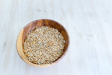 roasted peeled sunflower seeds in wooden dish on light table