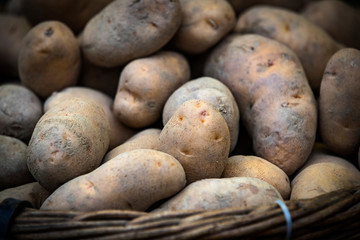 Raw potatoes in baskets on the market close up shot 