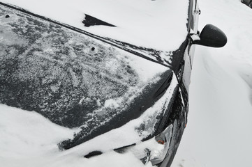 Close-up of a car under a snow in a parking lot