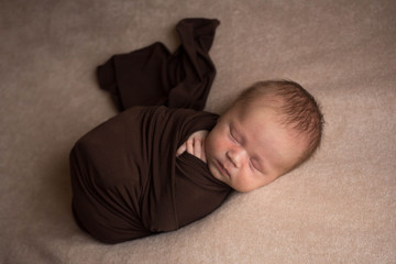 the first photo shoot. newborn child. newborn boy. baby's wrapped in a brown diaper