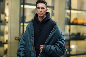 Fashionable man walk on the street near buildings. Wear blue jacket and all black. Winter, autumn...