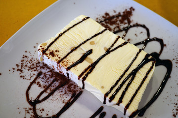 A slice of white semifreddo ice dessert with chocolate sauce in Tuscany 