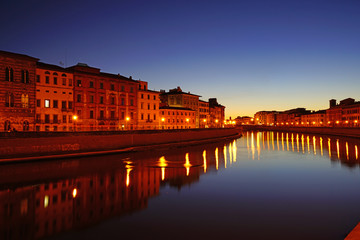 Fototapeta na wymiar Night view of colorful medieval buildings on the quay reflecting on the Arno River in Pisa, Tuscany, Italy