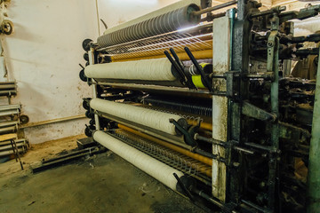 Wool thread production line. Spinning machinery with spindles and wool yarns 