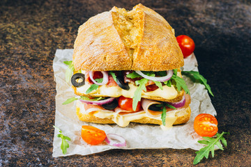 Fresh big ciabatta sandwich stuffed with prosciutto
