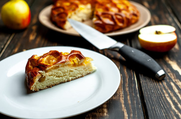 Fresh baked organic classic American apple pie with raisins, lying next to fruits, ingredients on wooden table. Country style