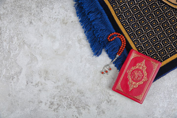 Muslim prayer beads, Quran, rug and space for text on grey background, top view