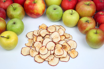Dried Apple slices surrounded by fresh apples on white background