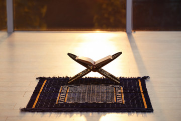Rehal with open Quran on Muslim prayer mat indoors