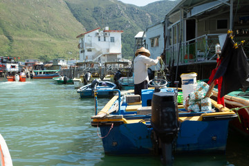 Fototapeta na wymiar Tai O Fishing Village, Lantau Island, Hong Kong, China, Fisherman holding fishing net on boat in water inside Tai O fishing village.