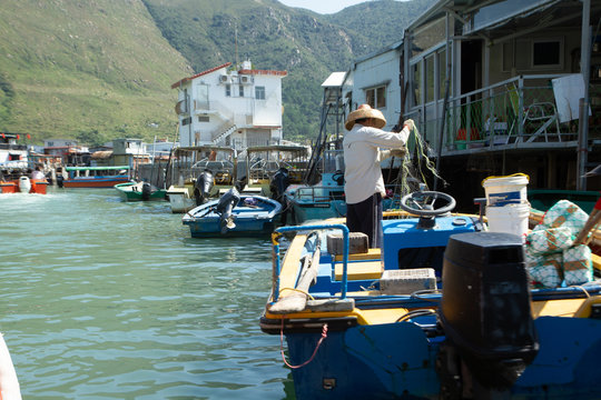 Tai O Fishing Village, Lantau Island, Hong Kong, China, Fisherman holding fishing net on boat in water inside Tai O fishing village.