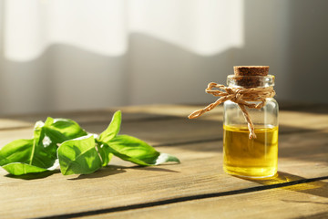 Bottle of essential basil oil on table against blurred background. Space for text