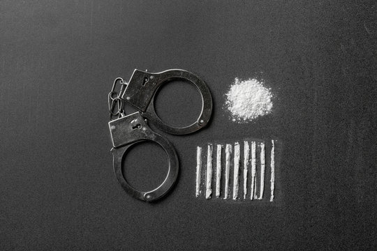 Flat lay composition with cocaine and handcuffs on black background