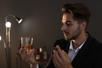 Young man with glass of whiskey and cigar at home