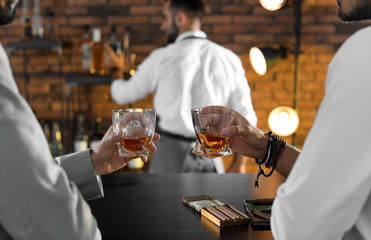 Friends drinking whiskey together in bar, closeup