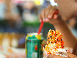 boy fed fast food bread with his hand and also drink
