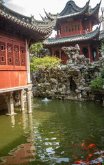 Vertical photo of building in Yu Yuan Garden, Shanghai China, koi fish are in pond in foreground.