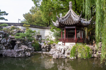 Pavilion, rocks and willow tree in Yu Yuan Garden, Shanghai China.