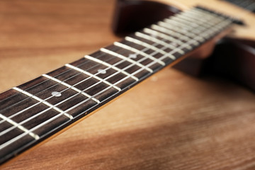 Fototapeta premium Modern electric guitar on wooden background, neck with strings in focus
