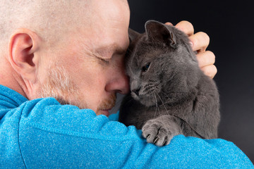 grey cat sitting on a man's shoulder