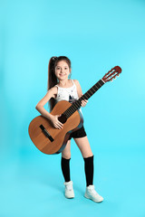 Cute little girl playing guitar on color background