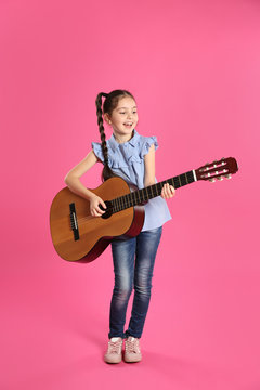 Cute little girl playing guitar on color background