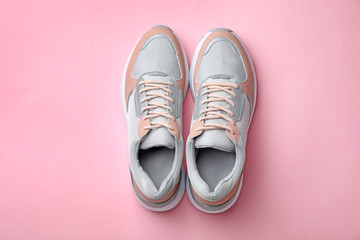 Pair of stylish sneakers on color background, top view