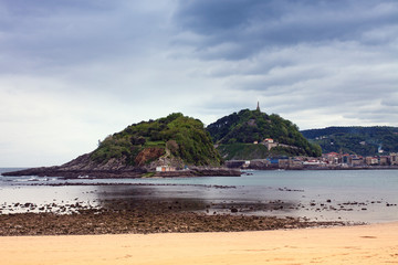 ISLOTE CON MONTAÑAS EN EL HORIZONTE Y PLAYA