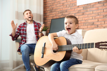 Father and son playing guitar and singing at home