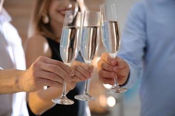 Friends clinking glasses with champagne at party indoors, closeup