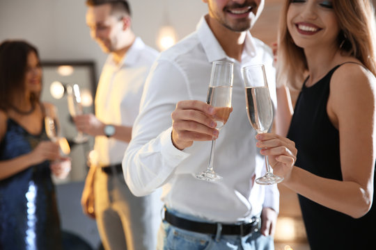 Couple clinking glasses with champagne at party indoors, closeup