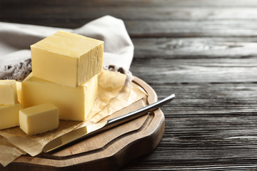 Wooden board with fresh butter and knife on table, space for text © New Africa
