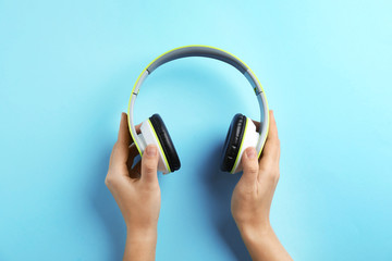 Woman holding headphones on color background, top view