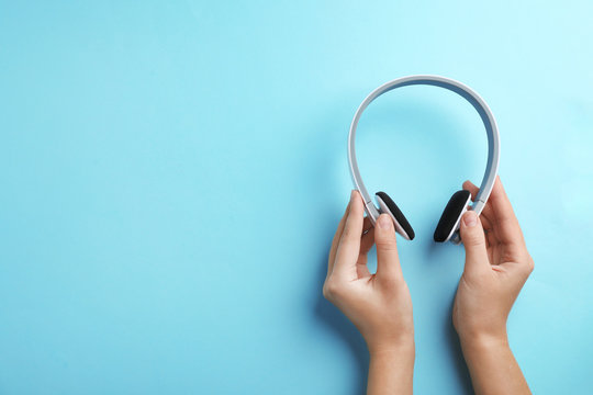 Woman holding headphones on color background, top view. Space for text