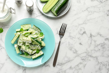 Plate with delicious cucumber salad served on marble table, top view. Space for text