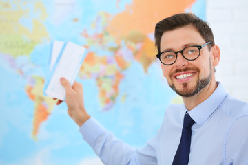 Male consultant holding tickets in travel agency. Space for text