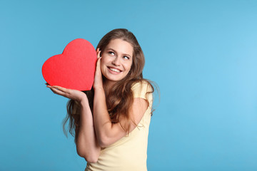 Portrait of young woman with decorative heart on color background. Space for text